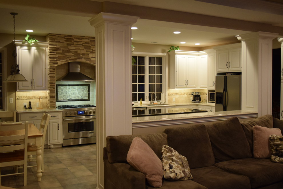 Example of a transitional ceramic tile kitchen design with an undermount sink, raised-panel cabinets, quartz countertops, beige backsplash, ceramic backsplash, stainless steel appliances and an island