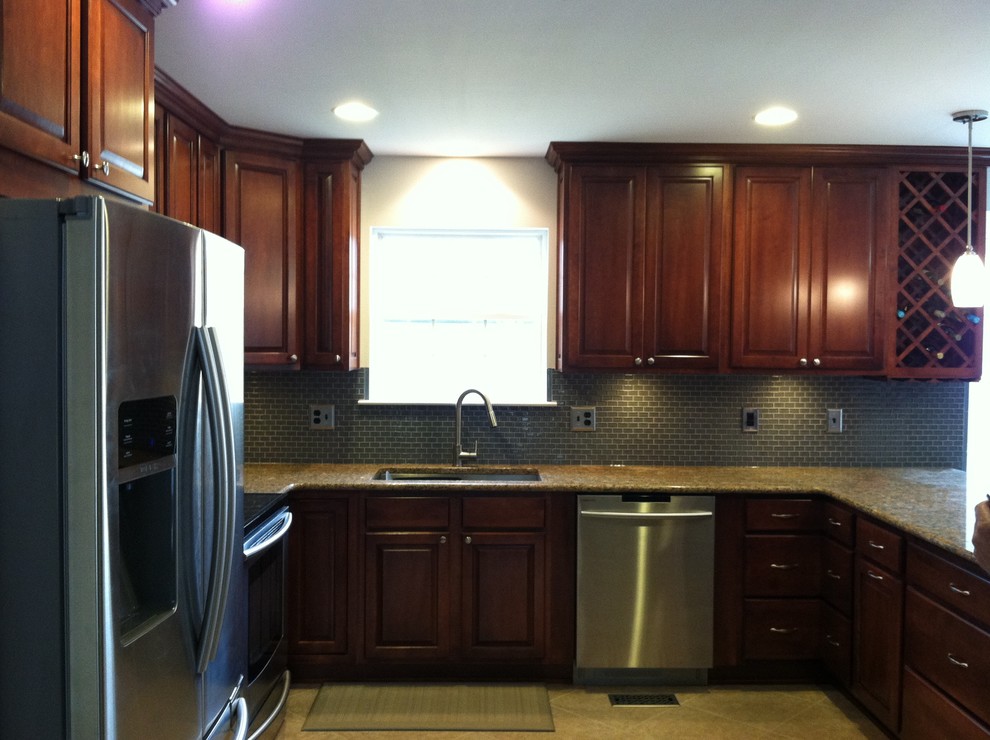 Example of a large transitional u-shaped ceramic tile and beige floor enclosed kitchen design with an undermount sink, raised-panel cabinets, dark wood cabinets, granite countertops, blue backsplash, ceramic backsplash, stainless steel appliances and a peninsula
