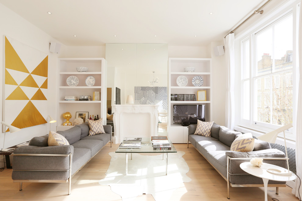 This is an example of a contemporary living room in London with white walls, light hardwood floors and a built-in media wall.