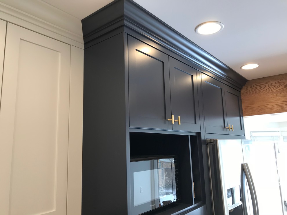 This is an example of a mid-sized traditional u-shaped eat-in kitchen in Calgary with an undermount sink, shaker cabinets, blue cabinets, quartz benchtops, white splashback, subway tile splashback, stainless steel appliances, medium hardwood floors, no island and brown floor.