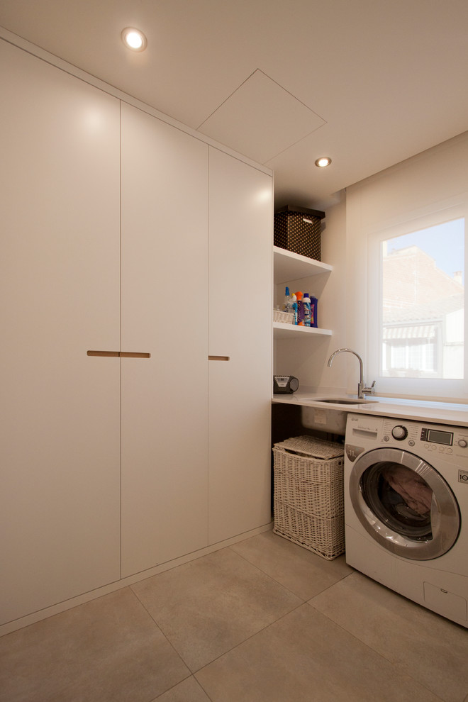 Design ideas for a small contemporary l-shaped dedicated laundry room in Other with a single-bowl sink, flat-panel cabinets, white cabinets, white walls, ceramic floors and a side-by-side washer and dryer.