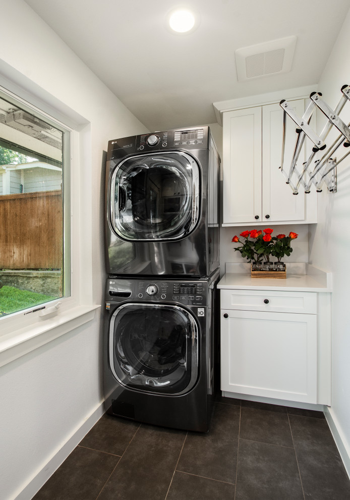 Design ideas for a mid-sized transitional single-wall dedicated laundry room in Dallas with white cabinets, quartz benchtops, white walls, porcelain floors, a stacked washer and dryer, grey floor, white benchtop and shaker cabinets.