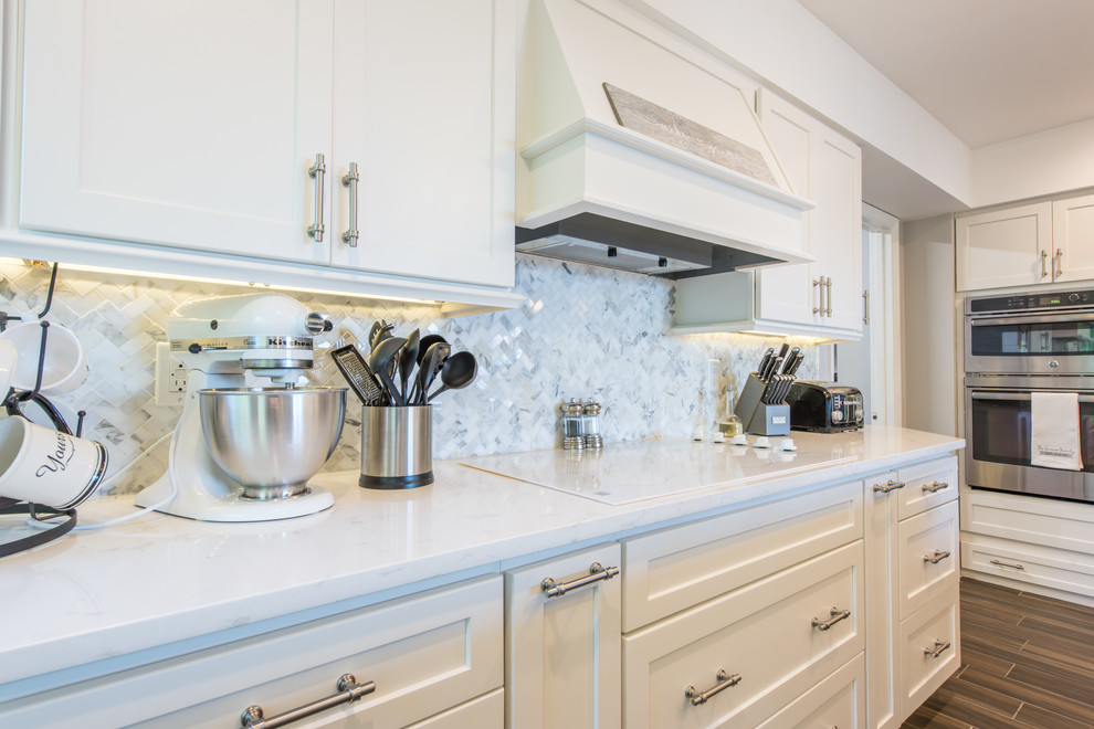 Large transitional u-shaped porcelain tile and brown floor eat-in kitchen photo with an undermount sink, shaker cabinets, white cabinets, quartz countertops, white backsplash, marble backsplash, stainless steel appliances and two islands