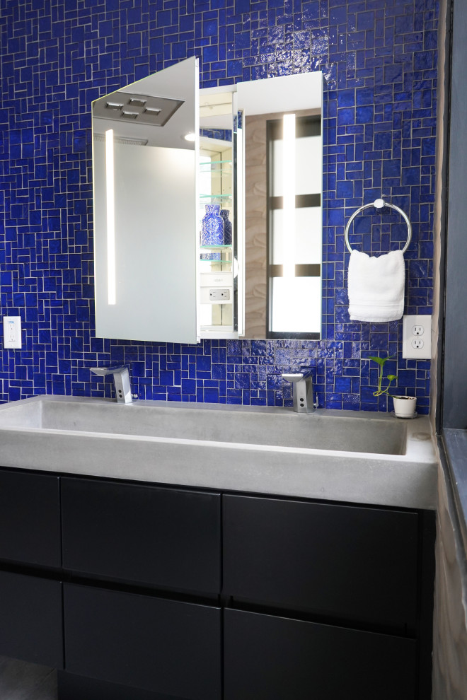 Design ideas for a mid-sized contemporary master bathroom in Atlanta with flat-panel cabinets, black cabinets, a curbless shower, a bidet, blue tile, glass tile, grey walls, porcelain floors, a trough sink, concrete benchtops, grey floor, an open shower, grey benchtops, a laundry, a double vanity and a floating vanity.