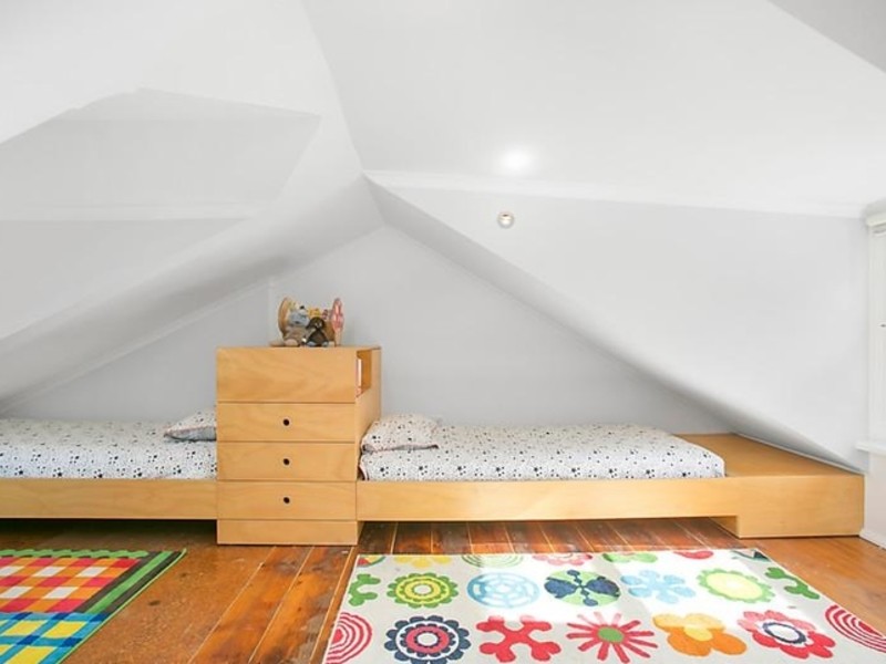 Small contemporary gender-neutral kids' bedroom in Sydney with white walls, medium hardwood floors and brown floor for kids 4-10 years old.