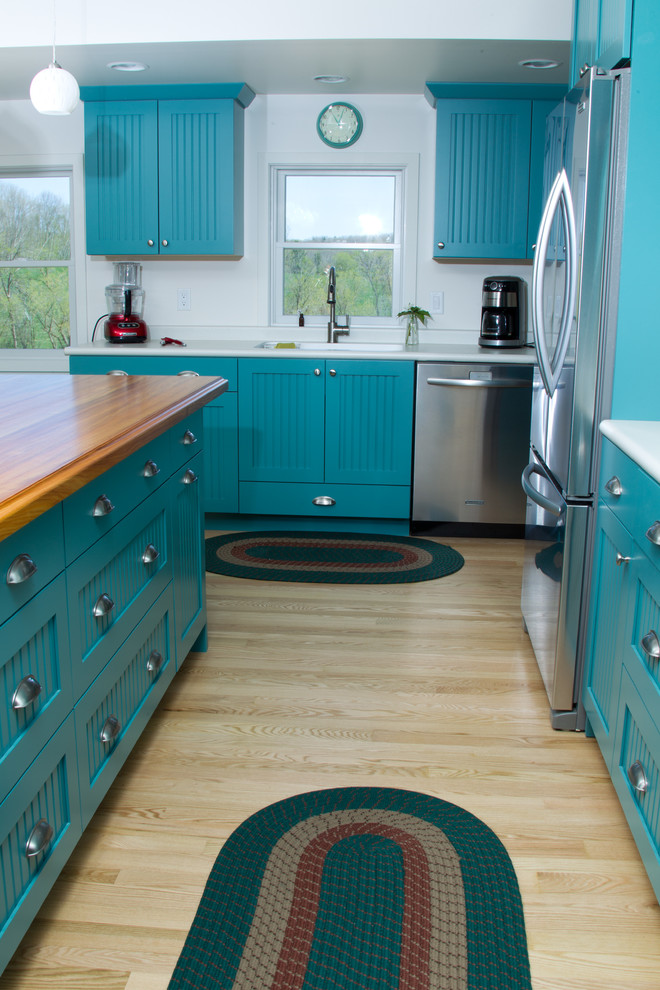Design ideas for a large arts and crafts galley eat-in kitchen in Minneapolis with an integrated sink, shaker cabinets, blue cabinets, wood benchtops, white splashback, stainless steel appliances, light hardwood floors and with island.