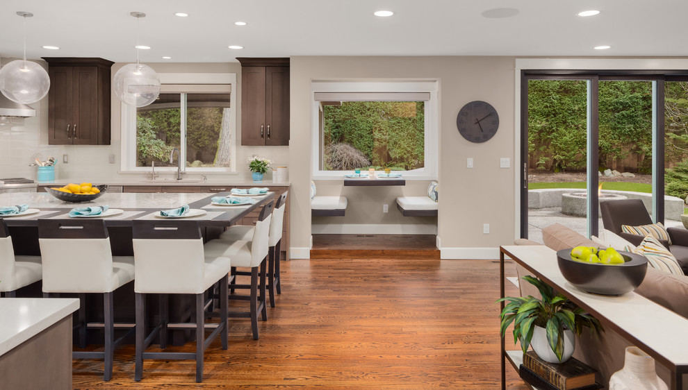 Large transitional u-shaped medium tone wood floor and brown floor eat-in kitchen photo in Seattle with a single-bowl sink, shaker cabinets, dark wood cabinets, quartzite countertops, gray backsplash, glass tile backsplash, stainless steel appliances, an island and white countertops