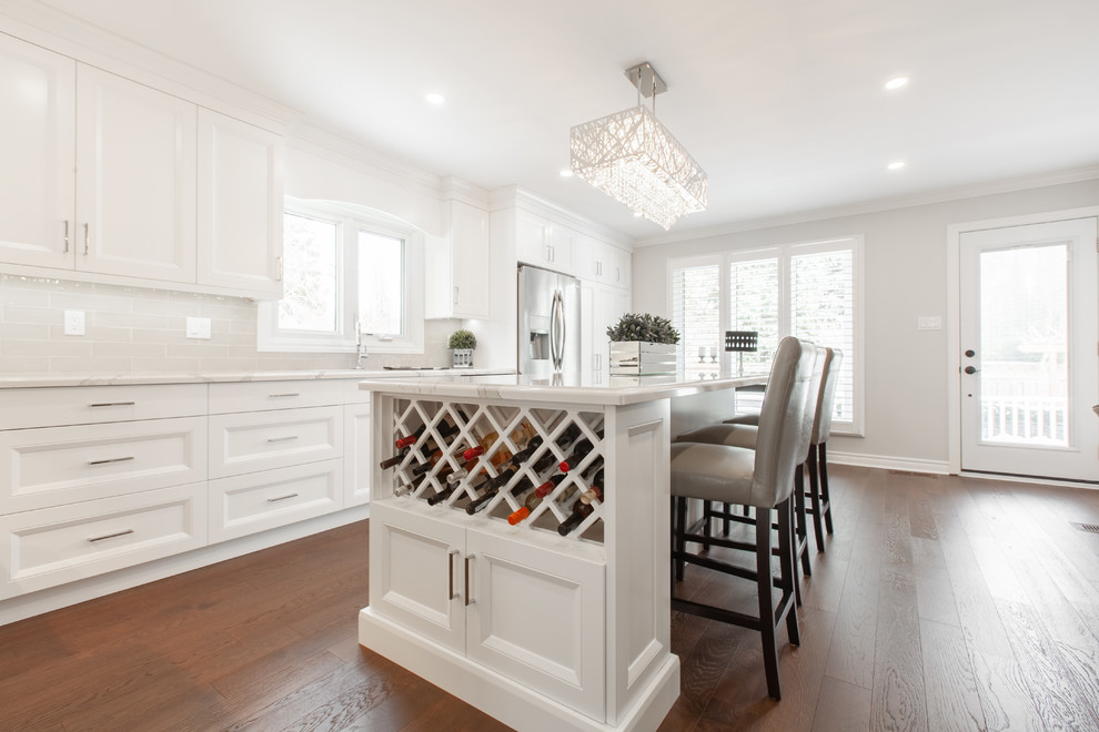 Enclosed kitchen - large transitional l-shaped medium tone wood floor and brown floor enclosed kitchen idea with an undermount sink, recessed-panel cabinets, white cabinets, quartz countertops, gray backsplash, ceramic backsplash, stainless steel appliances, an island and white countertops