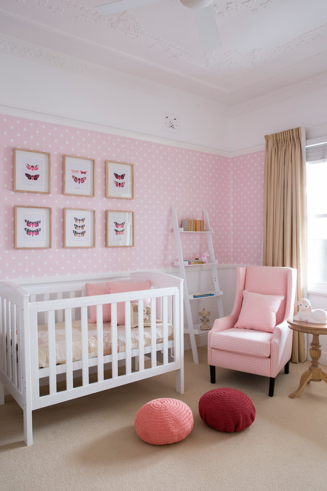 This is an example of a transitional nursery for girls in Sydney with pink walls, carpet and beige floor.