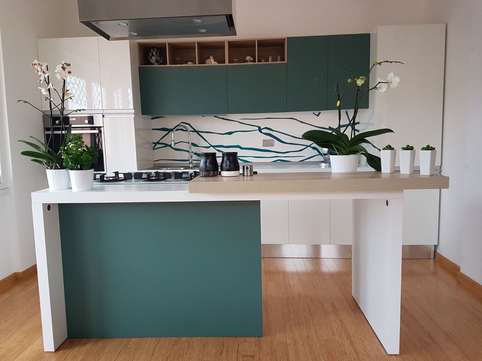 Photo of a small modern open plan kitchen in Rome with a drop-in sink, flat-panel cabinets, green cabinets, laminate benchtops, metallic splashback, medium hardwood floors and with island.