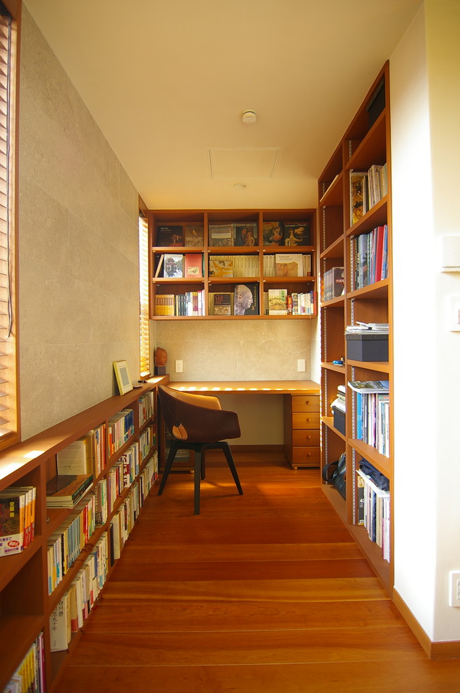 Photo of a midcentury study room in Other with beige walls, medium hardwood floors, no fireplace, a built-in desk and brown floor.