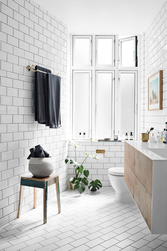 This is an example of a contemporary bathroom in New York with flat-panel cabinets, medium wood cabinets, white tile, subway tile, white walls, an integrated sink and white floor.