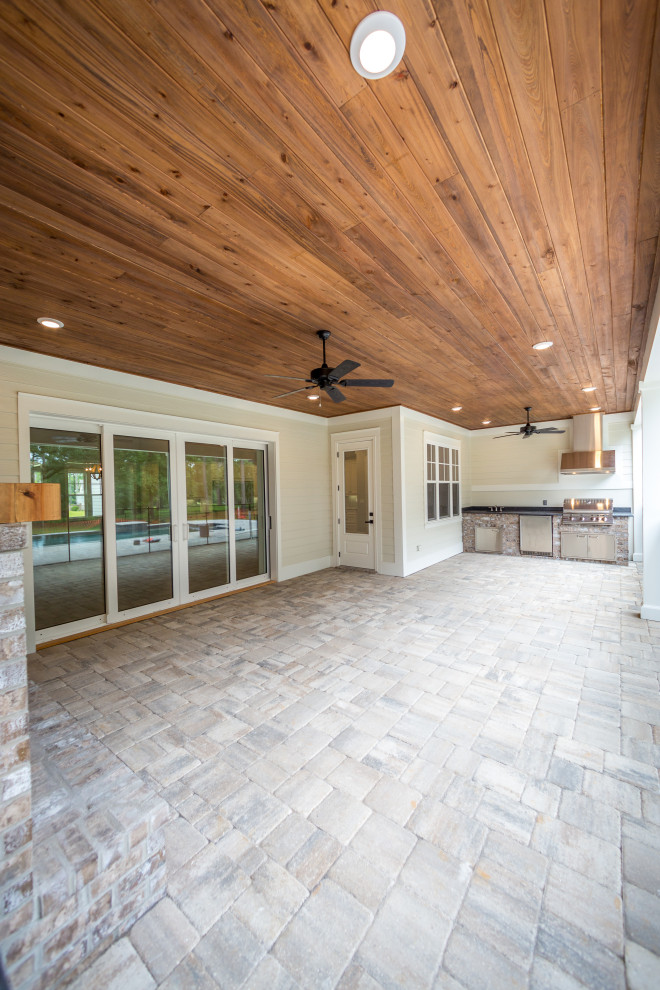 Exemple d'un porche d'entrée de maison arrière chic de taille moyenne avec une cuisine d'été, des pavés en béton et une extension de toiture.