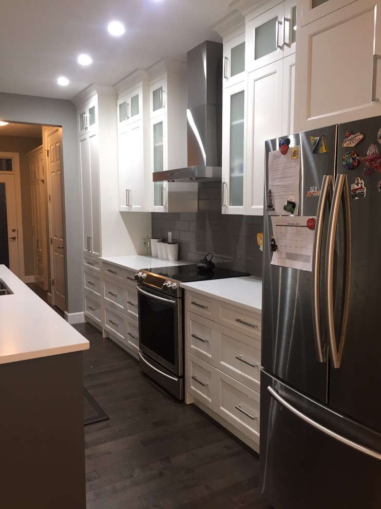 Inspiration for a mid-sized single-wall dark wood floor eat-in kitchen remodel in Calgary with an undermount sink, shaker cabinets, white cabinets, quartzite countertops, gray backsplash, subway tile backsplash, stainless steel appliances and an island
