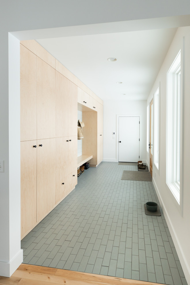 This is an example of a large scandinavian mudroom in Detroit with white walls, ceramic floors, a single front door, a white front door and grey floor.