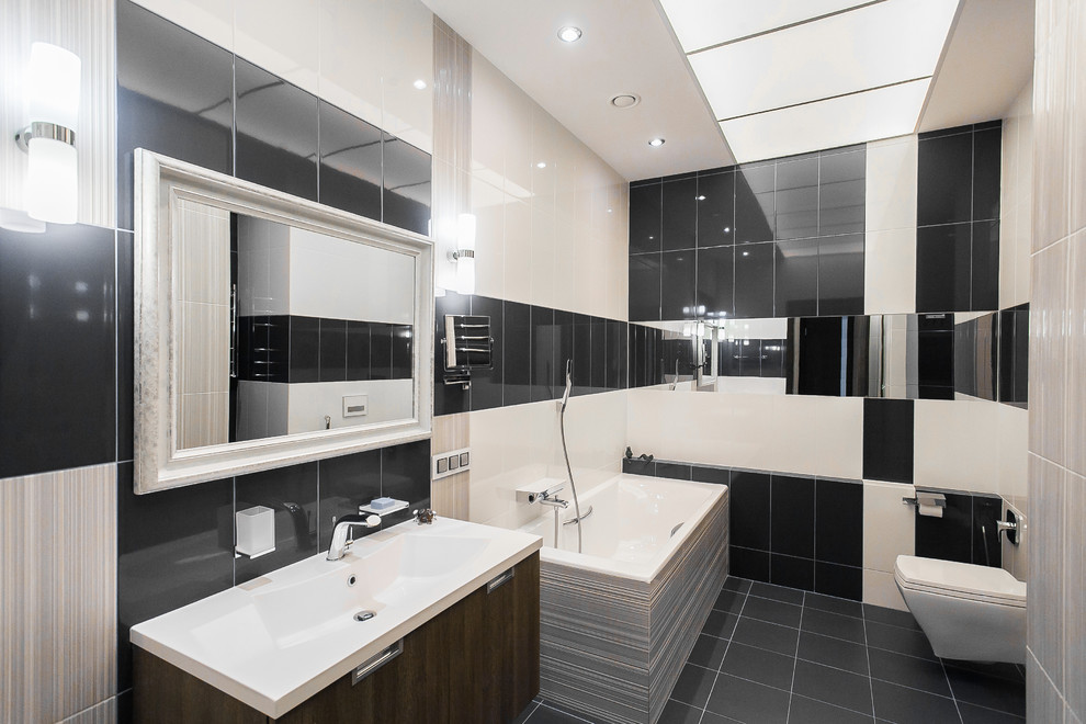 Photo of a mid-sized contemporary master wet room bathroom in Moscow with flat-panel cabinets, dark wood cabinets, a drop-in tub, a wall-mount toilet, black and white tile, ceramic tile, white walls, porcelain floors, a drop-in sink, solid surface benchtops, black floor and a hinged shower door.