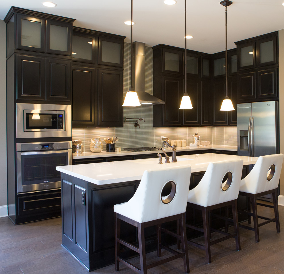 Large transitional l-shaped light wood floor and brown floor enclosed kitchen photo in Austin with an undermount sink, raised-panel cabinets, dark wood cabinets, quartzite countertops, gray backsplash, matchstick tile backsplash, stainless steel appliances, an island and white countertops