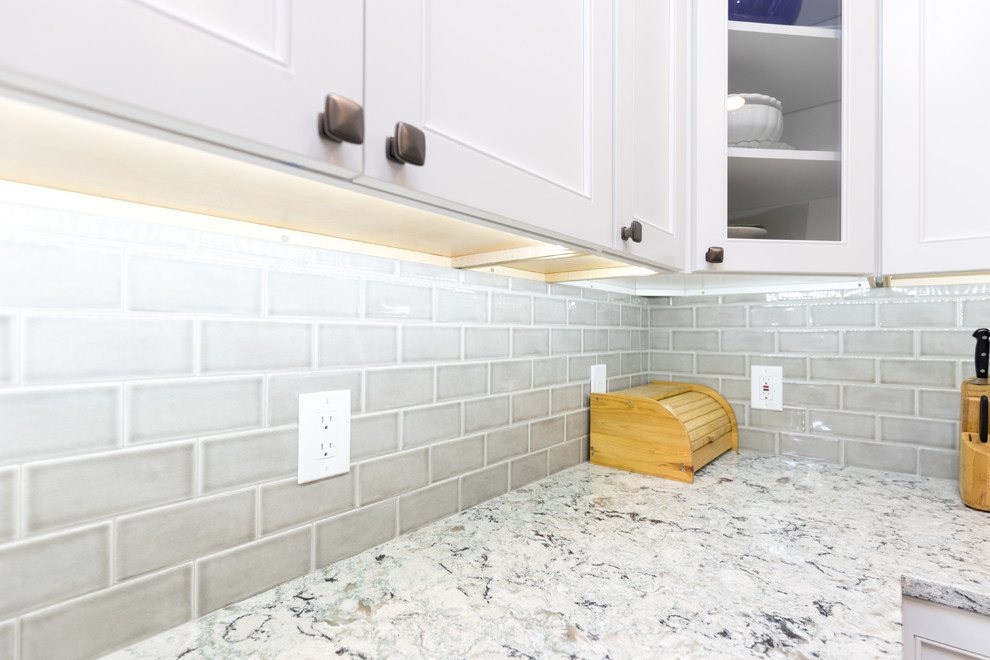 Example of a mid-sized transitional l-shaped porcelain tile and brown floor enclosed kitchen design in San Diego with an undermount sink, beaded inset cabinets, white cabinets, granite countertops, gray backsplash, ceramic backsplash, stainless steel appliances, no island and gray countertops