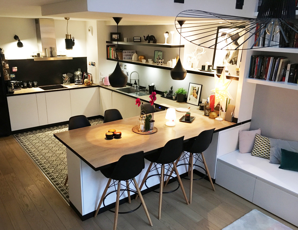 Design ideas for a mid-sized scandinavian u-shaped open plan kitchen in Paris with white cabinets, wood benchtops, white splashback, terra-cotta splashback, stainless steel appliances, with island, an undermount sink, flat-panel cabinets, cement tiles, grey floor and brown benchtop.