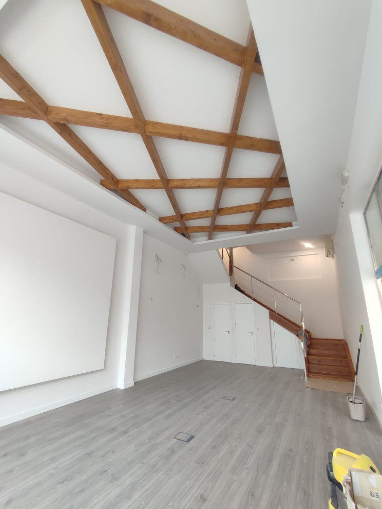 Immagine di una palestra multiuso minimalista di medie dimensioni con pareti bianche, pavimento in laminato e soffitto in legno