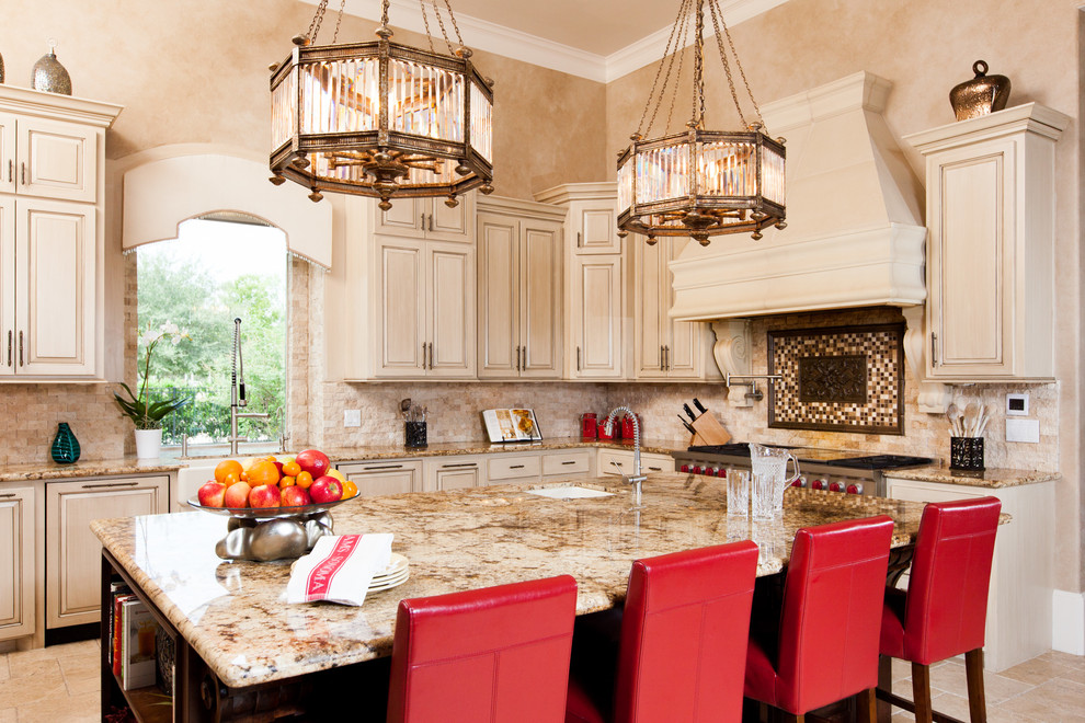 Photo of a mediterranean l-shaped kitchen in Houston with a farmhouse sink, raised-panel cabinets, beige cabinets, beige splashback, stainless steel appliances and with island.