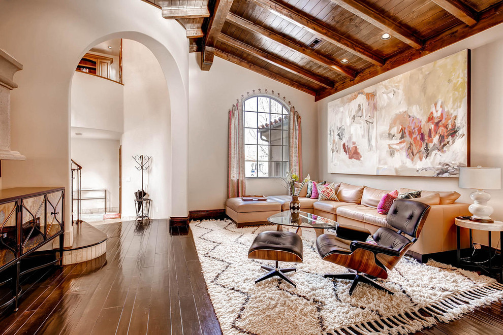 Inspiration for a mid-sized mediterranean open concept dark wood floor family room remodel in Denver with beige walls, a standard fireplace, a stone fireplace and a wall-mounted tv