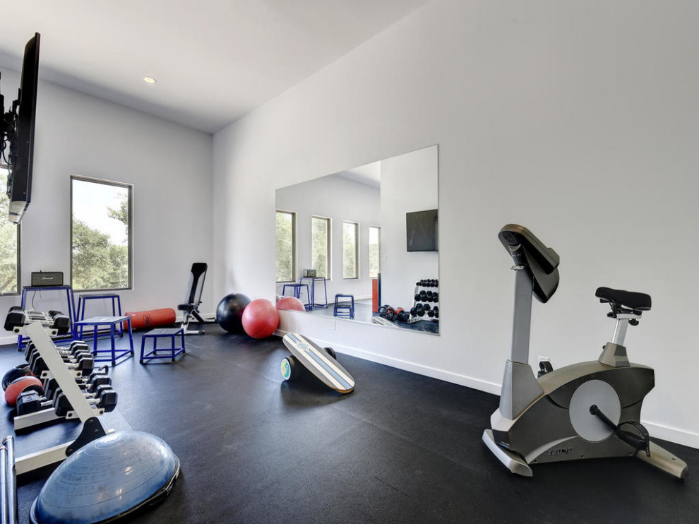This is an example of a large contemporary multipurpose gym in Austin with white walls and black floor.