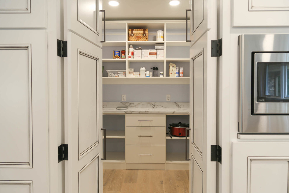 Mid-sized transitional u-shaped light wood floor and beige floor eat-in kitchen photo with an undermount sink, recessed-panel cabinets, white cabinets, quartzite countertops, black backsplash, porcelain backsplash, stainless steel appliances, an island and white countertops
