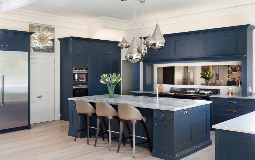 Design ideas for a transitional eat-in kitchen in Cheshire with beaded inset cabinets, marble benchtops, mirror splashback, stainless steel appliances, light hardwood floors, with island and white benchtop.