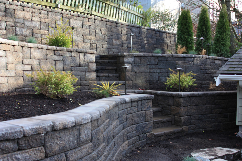 Photo of a mid-sized traditional backyard partial sun xeriscape for summer in Seattle with a retaining wall and concrete pavers.