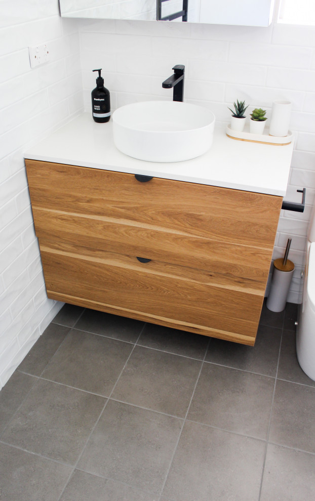Inspiration for a small modern master bathroom in Perth with flat-panel cabinets, dark wood cabinets, a drop-in tub, a corner shower, a one-piece toilet, white tile, ceramic tile, white walls, porcelain floors, a vessel sink, engineered quartz benchtops, grey floor, a hinged shower door and white benchtops.