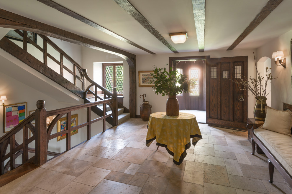 Immagine di un ingresso o corridoio stile marino con pareti beige, una porta singola, una porta in legno scuro, pavimento beige e travi a vista