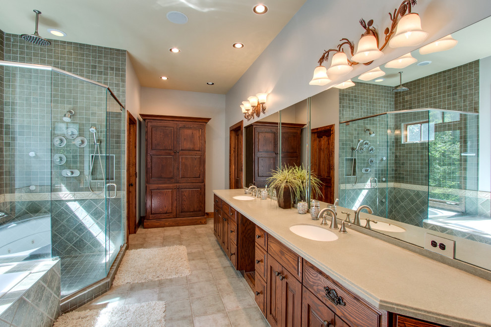 Design ideas for a mid-sized traditional master bathroom in Nashville with raised-panel cabinets, dark wood cabinets, a drop-in tub, a corner shower, gray tile, ceramic tile, grey walls, ceramic floors, an undermount sink, solid surface benchtops, grey floor and a hinged shower door.