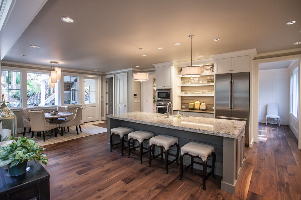 This is an example of a mid-sized transitional l-shaped open plan kitchen in Portland with an undermount sink, recessed-panel cabinets, white cabinets, granite benchtops, multi-coloured splashback, mosaic tile splashback, stainless steel appliances, dark hardwood floors, with island and brown floor.