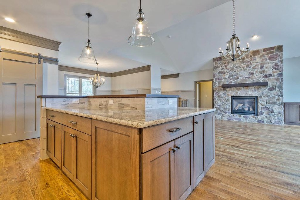 Example of a mid-sized medium tone wood floor kitchen design with shaker cabinets, medium tone wood cabinets, granite countertops, gray backsplash, stainless steel appliances and an island