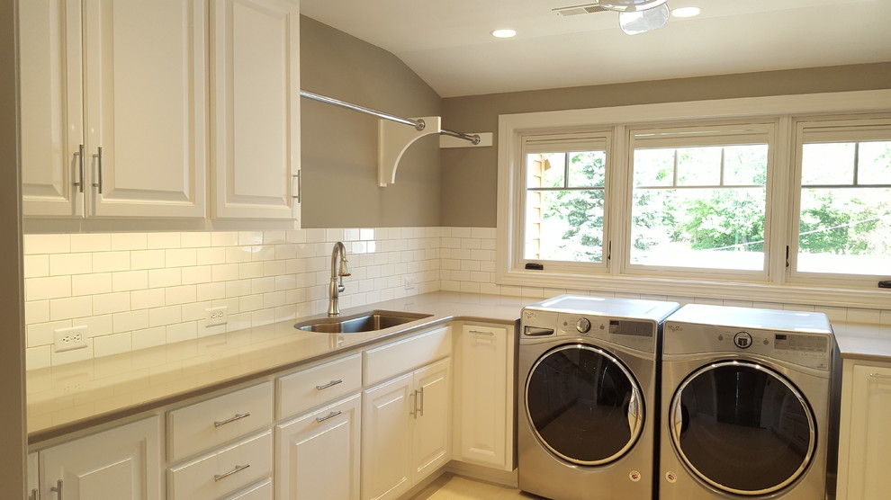 Design ideas for an expansive arts and crafts u-shaped dedicated laundry room in Other with an undermount sink, raised-panel cabinets, white cabinets, solid surface benchtops, grey walls, ceramic floors, a side-by-side washer and dryer, beige floor and beige benchtop.