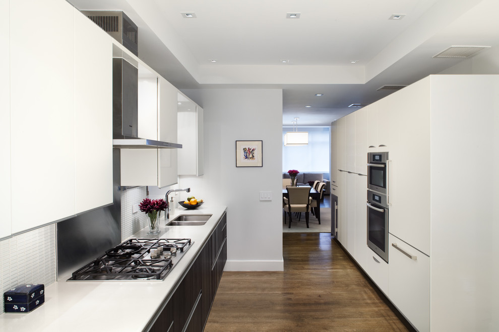 Modern kitchen in New York with a double-bowl sink, flat-panel cabinets and white splashback.
