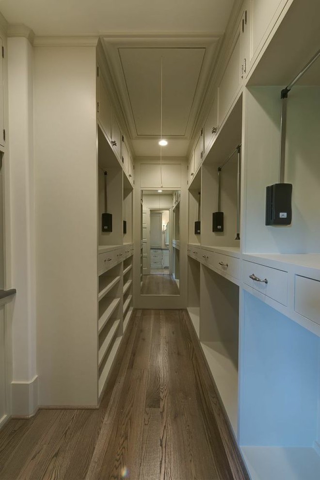 Photo of a large mediterranean men's walk-in wardrobe in Houston with beige cabinets and medium hardwood floors.