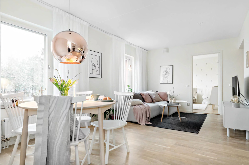 Mid-sized scandinavian open concept living room in Stockholm with white walls, light hardwood floors, a freestanding tv and beige floor.