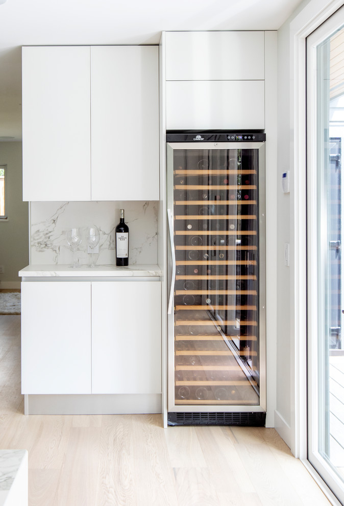 Small modern wine cellar in Vancouver with light hardwood floors and display racks.