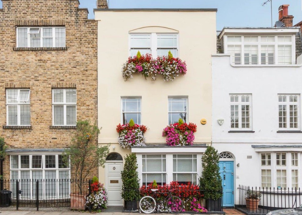 Inspiration for a traditional three-storey beige townhouse exterior in London with a flat roof.
