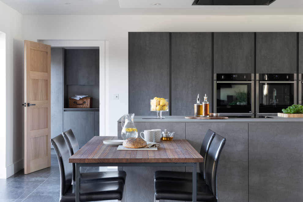 Design ideas for a large modern eat-in kitchen in Oxfordshire with a double-bowl sink, flat-panel cabinets, grey cabinets, panelled appliances, ceramic floors, with island and black floor.