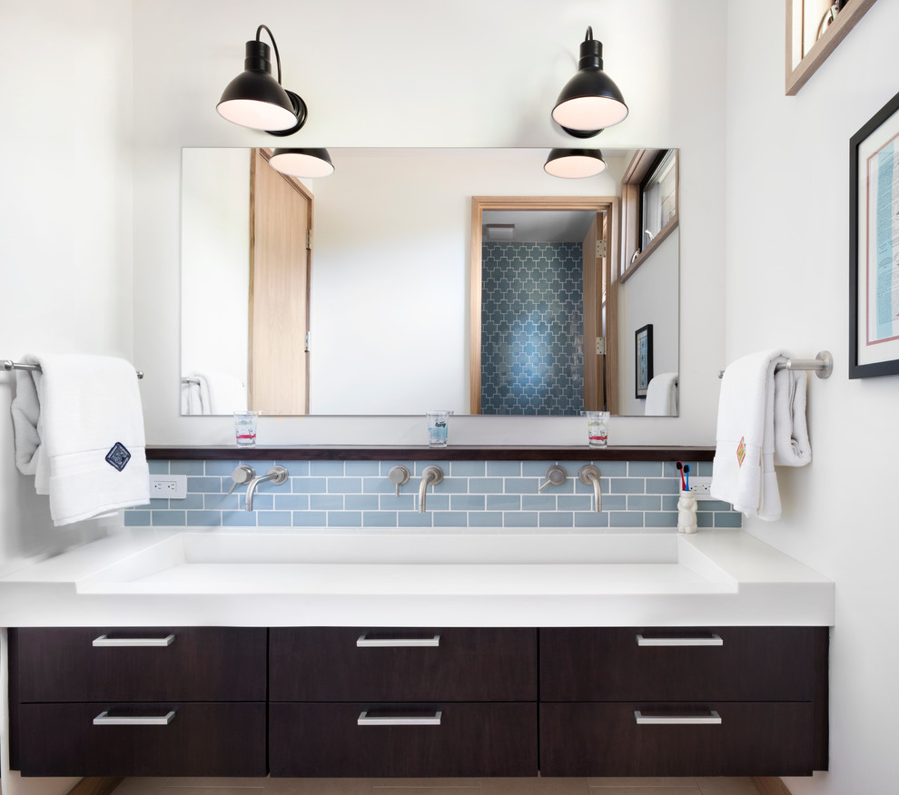 This is an example of a large transitional 3/4 bathroom in San Francisco with flat-panel cabinets, dark wood cabinets, white walls, porcelain floors, a trough sink, solid surface benchtops, a one-piece toilet, blue tile and subway tile.