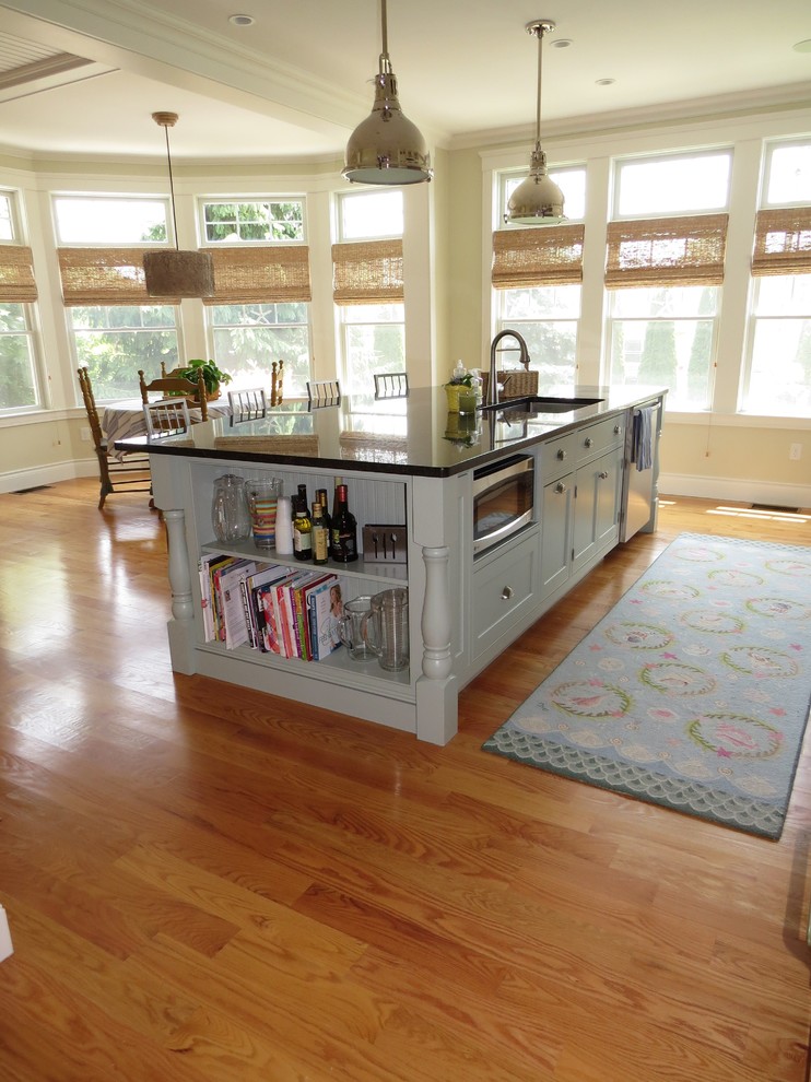 Photo of a large beach style galley open plan kitchen in Portland Maine with an undermount sink, beaded inset cabinets, grey cabinets, granite benchtops, stainless steel appliances, medium hardwood floors and with island.