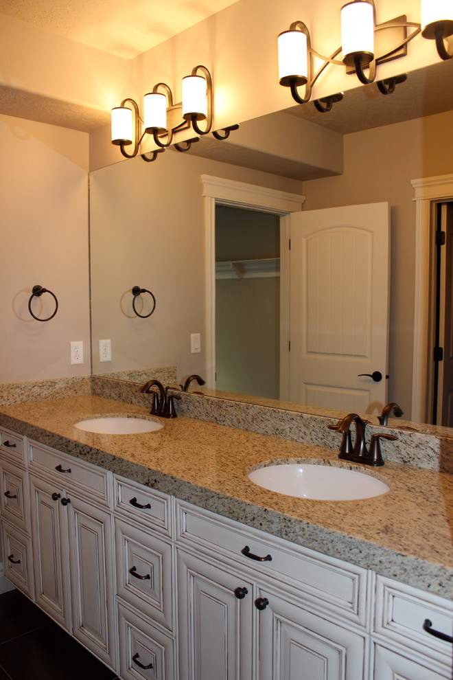 This is an example of a large traditional kids bathroom in Salt Lake City with raised-panel cabinets, distressed cabinets, granite benchtops, an undermount sink, an alcove tub, a shower/bathtub combo, a two-piece toilet, gray tile, ceramic tile, grey walls and ceramic floors.