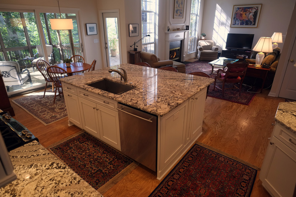 Large transitional l-shaped open plan kitchen in Atlanta with flat-panel cabinets, white cabinets, granite benchtops, with island, a double-bowl sink, multi-coloured splashback, mosaic tile splashback, stainless steel appliances and light hardwood floors.