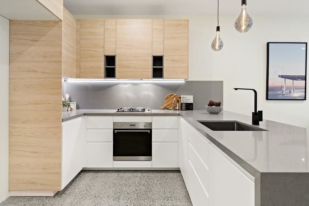 Contemporary u-shaped kitchen in Sydney with an undermount sink, flat-panel cabinets, light wood cabinets, grey splashback, a peninsula, grey floor and grey benchtop.