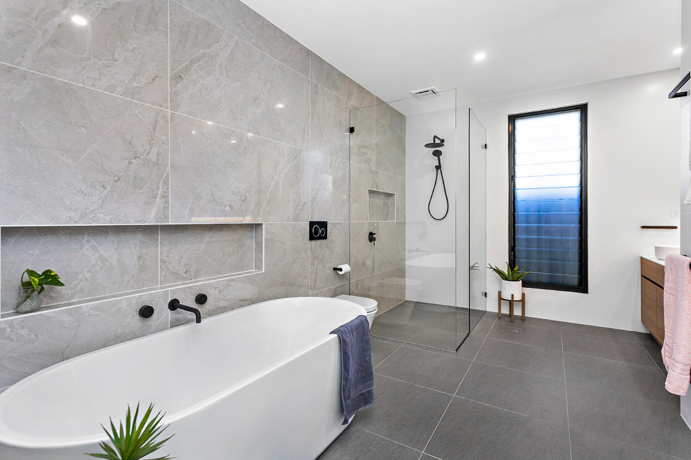 Inspiration for a mid-sized contemporary master bathroom in Wollongong with flat-panel cabinets, medium wood cabinets, a built-in vanity, a corner shower, a wall-mount toilet, gray tile, white walls, porcelain floors, a vessel sink, grey floor, a hinged shower door, white benchtops, a niche and a double vanity.