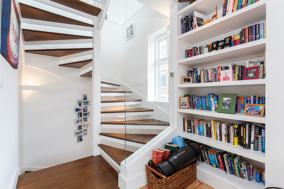 Photo of a small contemporary wood curved staircase in London with open risers.