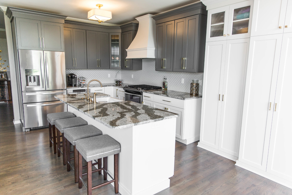 Eat-in kitchen - mid-sized transitional l-shaped medium tone wood floor eat-in kitchen idea in Philadelphia with a farmhouse sink, shaker cabinets, white cabinets, quartz countertops, gray backsplash, porcelain backsplash, stainless steel appliances and an island